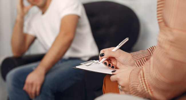 Man sitting in the psychologist's office and talking about probl In the psychologist's office. Man and woman talking